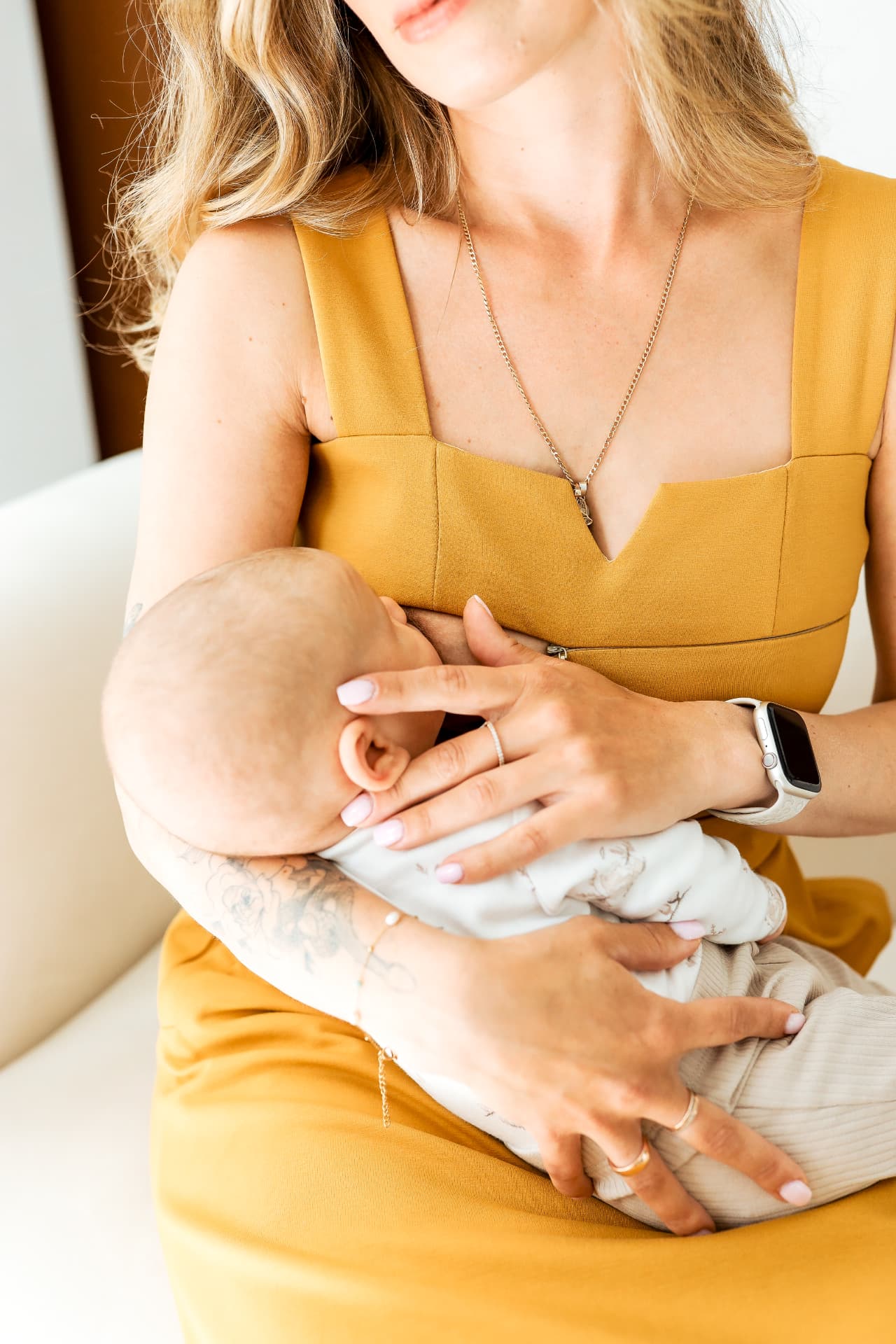 A mother nursing her baby in a mustard nursing dress