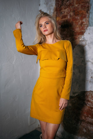 Beautiful blond woman in a mustard yellow two-piece dress with ruffle 