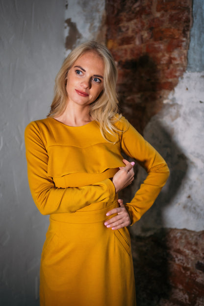 Beautiful blond woman in a mustard yellow two-piece dress with ruffle 