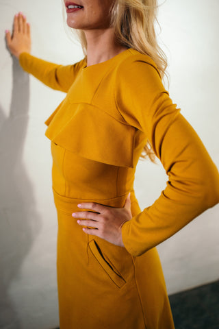 Beautiful blond woman in a mustard yellow two-piece dress with ruffle 