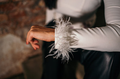 woman showing her white long sleeved top with feathers