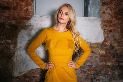 Beautiful blond woman in a mustard yellow two-piece dress with ruffle 