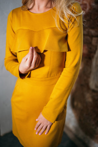 Beautiful blond woman in a mustard yellow two-piece dress with ruffle 