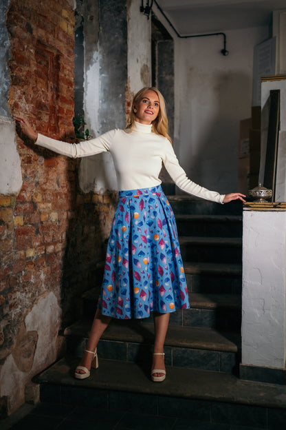 beautiful blond lady in a white turtleneck and baby blue colorful skirt in white heels