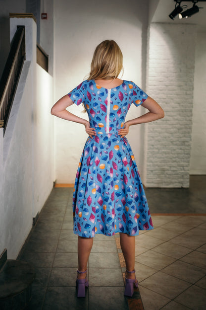 beautiful blond lady in a colorful baby blue dress and purple heels. white zipper on the back