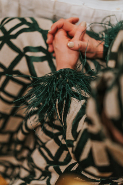 lady sitting in the emerald green feather dress with crossed arms