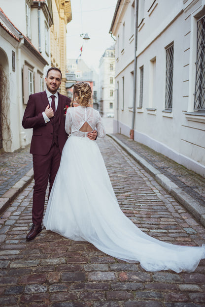 a couple on their wedding day - man in his bordeaux tuxedo and lady from the back in her lace wedding gown