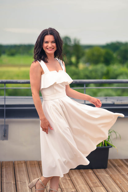 beautiful woman in a white two piece dress with corset top with a ruffle over the breast seam and long flowy skirt