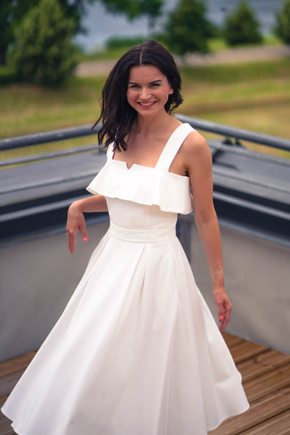 beautiful woman in a white two piece dress with corset top with a ruffle over the breast seam and long flowy skirt