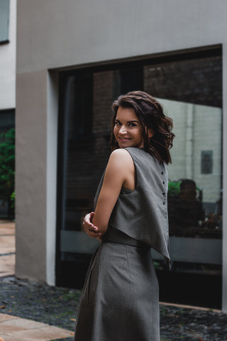 beautiful woman on a sunny day, wearing three piece dress - two tops and gray brown triangle skirt together with black heels
