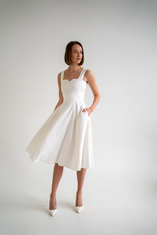 beautiful woman in a white two piece dress with corset top and long flowy skirt in white heels