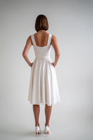 beautiful woman in a white two piece dress with corset top and long flowy skirt in white heels, picture from the back, she has nice bob haircut