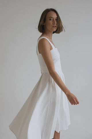beautiful woman in a white two piece dress with corset top and long flowy skirt in white heels, just spinning around in a white studio